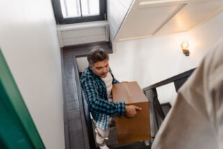 Young man climbing stairs with cardboard box.