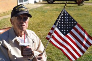 Elderly man sitting outdoors with the American Flag